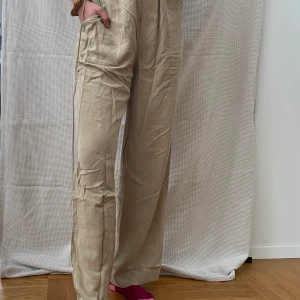 ACNE beige tunna byxor  - Dessa byxor från ACNE är långa, fladdriga i tyget, tunna, skönt material och har två stora fickor på vardera sida. Ej knappar eller resår upptill utan ett band som man drar åt efter önskemål. Frakt tillkommer <3