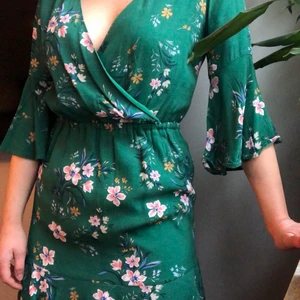 Sommarens snyggaste omlottklänning! - Grön blommig omlottklänning, slutar strax ovanför knät. I viskos, gott skick! Pris exkl frakt