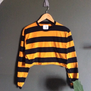 Orange/black striped croptop - Croppade tröjan själv och hemmen är rå, men tyget rullar up sig och skapar en “naturlig hem” som man man se på bild #2. Väl använd men bra kvalitet