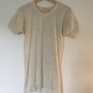 T-shirt randig storlek M - Beige randig stickad T-shirt. Har ett litet hål på baksidan med ingeting som märks.