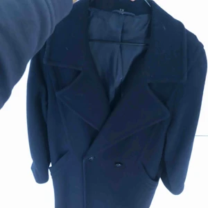  - Använd men i gott skick, marinblå lång kappa i ull. Jag är 165cm och den passar mig bra! Säljer då den inte kommer till användning. Svårt att få med hela på bild, hör av er så skickar jag fler bilder!!!!! 🌼