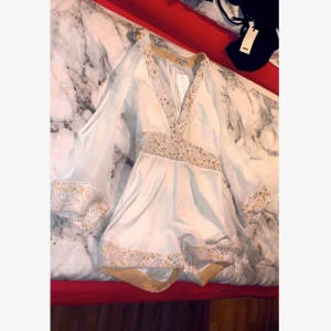  - Jätte fin playsuit som är v-ringad & öppen vid armarna. Passar utmärkt till sommarens alla fester. Prislapp sitter kvar.  Helt oanvänt & i bra skick. Storlek 12 (alltså storlek M) 