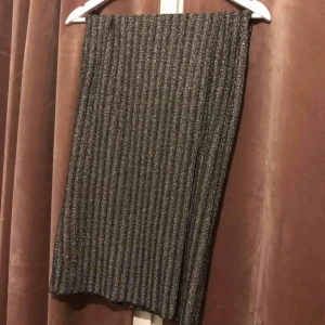  - Glittrig långkjol i stretchigt material och med slits längs ner. Resår i midjan. 