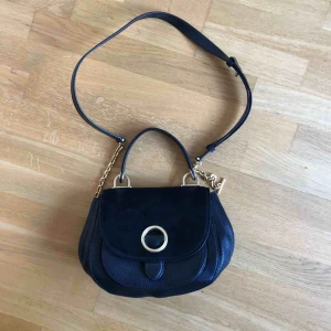  - Liten väska från Michael Kors, passar perfekt att ha till vardag även till helger. Väskan är av läder med mocka detaljer. Väskan är endast använd ett fåtal gånger och köptes för ca 1 år sedan på nk. Nypris: 2999:- 