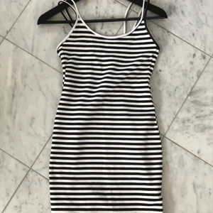 Tight klänning - Svart och vit randig tight klänning. Går ungefär nästan ner till knäna. Banden i ryggen är korsade. Mycket gott skick, endat använd ett fåtal gånger. 