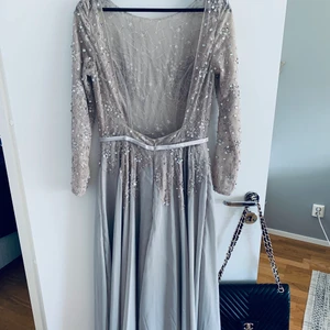 Vacker balklänning med öppen rygg!  - Fantastisk fin balklänning. Aldrig använd!  Öppen rygg och paljett- och glitterdetaljer.  Ljusrosa/beige i färgen men samtidigt lite åt det silvriga hållet.  Jag är 180 cm lång och väger cirka 65 kg. Sitter helt perfekt!  