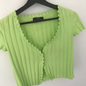 Tröja - En söt och fin topp från bershka! Den är som lite ”ribbad” som man ser på bilderna, den är rätt så urringad och har en grön/gul färg. Säljer för att jag inte använder den längre. Köpare står för frakt. 