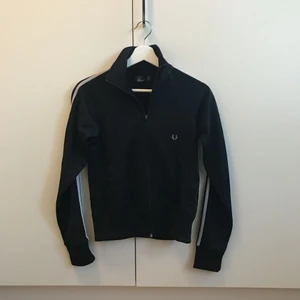  - Svart Fred Perry jacka/track jacket i storlek 38. Köpt för ett par år sedan men är knappt använd, så den är i väldigt bra skick . Istället för vita detaljer är de ljusgrå på den här vilket är snyggt! Med detaljer så menar jag strecken på ärmarna samt loggan på framsidan🌺