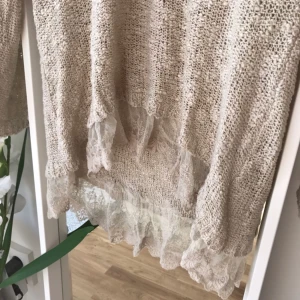  - Fin stickad tröja med volang i spets nertill. Använd ett fåtal gånger.  Kan skickas mot frakt kostnad