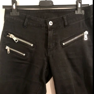  - Svarta jeans från Mango med silvriga dragkedjor på höfterna, supermjuka och sköna i tyget! Byxorna är tighta/smala hela vägen ner och har mycket stretch, passar storlek 38-40. 