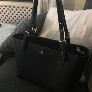  - Äkta Tory Burch väska köpt på Jackie, har originalpåsen kvar som väskan kom i.  Svart med gulddetaljer  Modell: York Buckle Tote