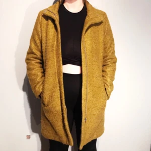  - Gul/grön melerad kappa i ullblandning i storlek 38 från Monki säljes för 200kr, frakt tillkommer. Kappan är använd 2 gånger och är därav i väldigt fint skick. Betalning sker via swish.   Pris: 200kr  Storlek: 38 