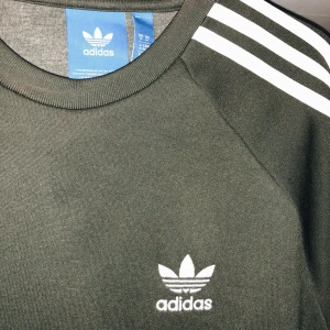  - En långärmad Adidas original tröja i färgen grön, riktigt snygg passar både kille och tjej. 