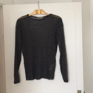  - Köparen står för frakt. Svart/silverglittrig transparant långärmad. 