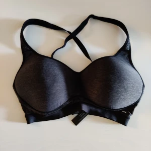 SportBH  - Svart/grå sportbh med korsad rygg och spänne bak från Hunkemöller. Storlek 75F. Sparsamt använd. Skickar spårbart med PostNord. 
