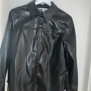 Svart läder (imitation) skjorta/jacka i storlek 38 aldrig använd. Frakt betalas själv. 
