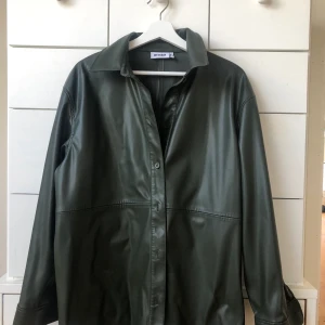 Skjorta i skinn från weekday - Säljer denna mörkgröna skinnskjorta från weekday i storlek M. Använd ett fåtal gånger.