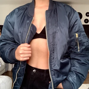 Bomberjacka - Skitcool oversixe bomberjacka. Jackan är gråblå med orange inuti. Ganska oversize i storleken. Skulle nog passa S/M/L beroende på hur man vill att den ska sitta. 