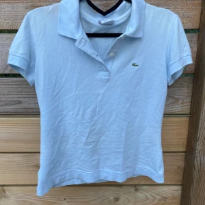 Ljus blå piké tröja från Lacoste storlek 38 - Säljer min fina Lacoste piké tröja då den inte passar längre. 