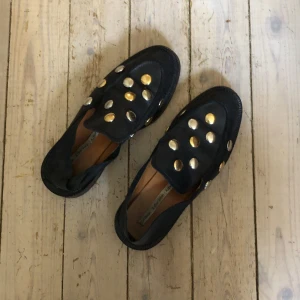 &Other stories skor - Fina &Other stories loafers/slip ins säljes! Kan användas som både loafers eller slip in toffla. Svart läder med nitar i guld / silver. Använda men i gott skick! Kan skickas mot fraktkostnad eller mötas i sthlm.