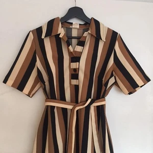 Randig retroklänning - Säljer nu denna läckra retroklänningen! Kortärmad, knappar o krage vid halsen och matchande midjeskärp. Superfint skick! Materialet är tunnare polyester. Skriv för fler bilder eller mått ❤