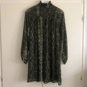 Klänning i ormskinns-mönster - Grön klänning från HM, använd en gång hade skärp till i midjan- tips! 