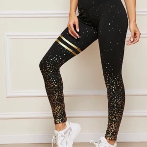 Träningstights  - Svarta träningstights med superfina coola gulddetaljer. Helt nya och oanvända. Säljes pga att de aldrig kommer komma till användning. 