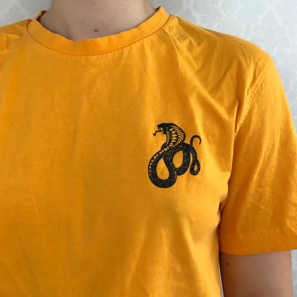 Tröjan är gul med tryck som förställer ormar. Frakt ingår. T-shirts.