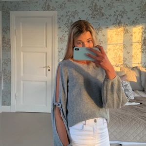 Tröja - Säljer denna grå stickade tröja som är öppen i ärmarna med rosetter, vilket är en väldigt fin detalj! Väldigt luftig och skön tröja! Pris: 100 kr. FRAKT TILLKOMMER💗🧚🏼