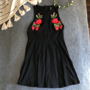 Klänning - Klänning i moccaimitation med blomdetaljer. Frakt betalas av köpare. 