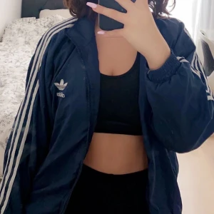 Adidas- blå track  - Adidas track jacket, marinblå. passar att slänga över t allt, gör en basic outfit lite roligare. 