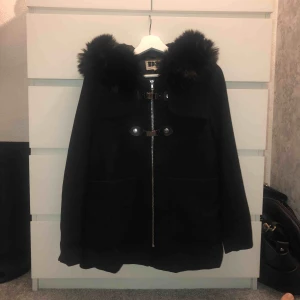  - En fin höst/vinter kappa från Dennis Maglic. Den slutar precis nedanför rumpan på mig som är 1,64 lång. Fuskpäls på luvan. Man stänger med dragkedja och så finns det 2 spännen upp till. Nypris: 1899kr. Köparen står för frakt.