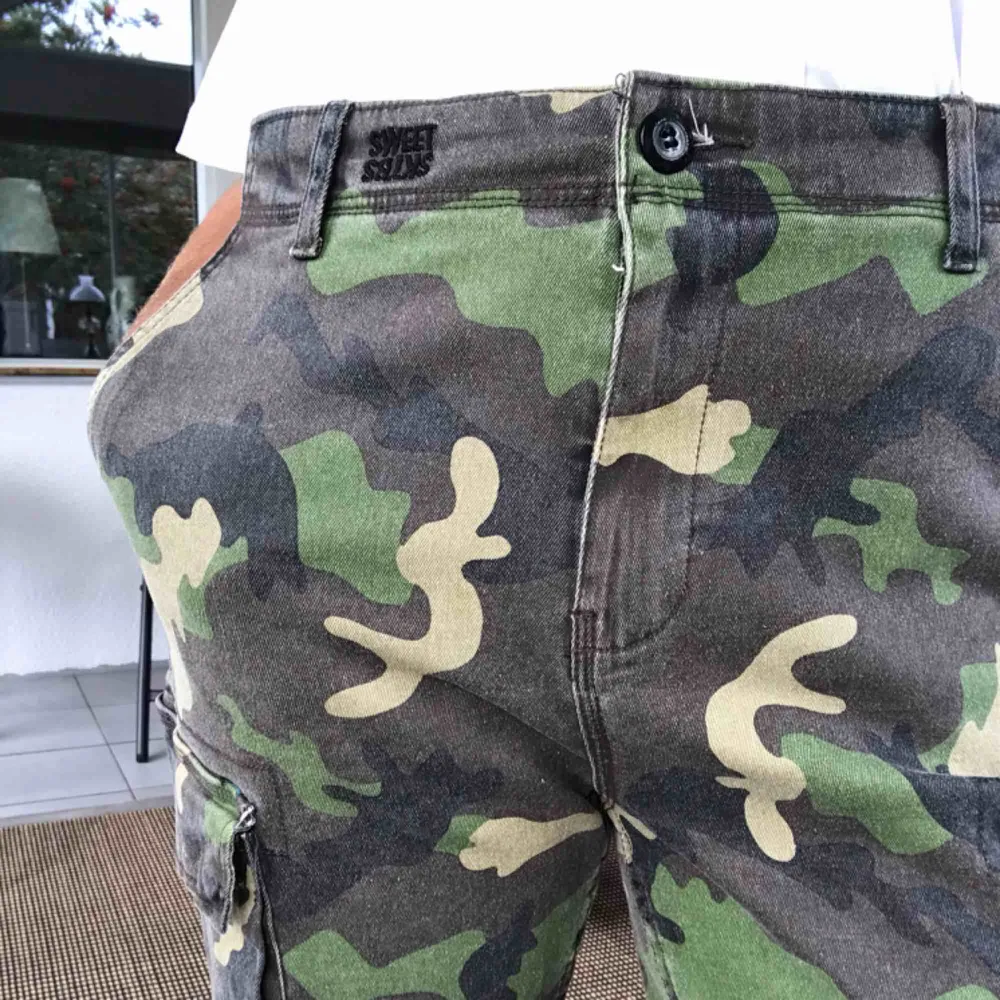 Unisex-shorts i militärmönster från SWEET SKTBS. Fickor på båda sidor. Supersköna. Använda ett fåtal ggr.. Shorts.