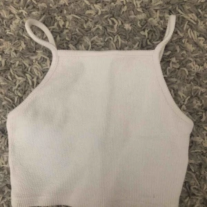  - En vit cropped topp som är halterneck i modellen. Toppen är ifrån Topshop