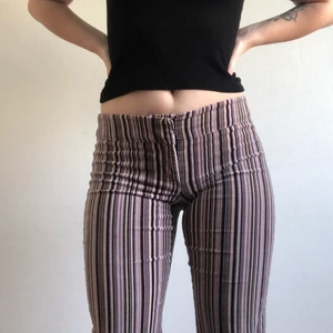 De perfekta lågmidjade byxorna!!  - Lågmidjade randiga byxor med lite bootcut. ÄLSKAR DEM!! Materialet är velour-liknande. Kan skicka närmre bild på tyget vid intresse. Står storlek 38 men jag på bilden är storlek 38-40 🥰 färgerna på ränderna är svart, lila, brunt och beige/vit. Har köpt de 2hand. 