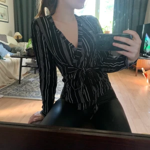 Omlott-blus - Randig blus med omlottknytning. Både knapp, litet snöre och stort band för att hålla ihop den. Blankt material ❤️