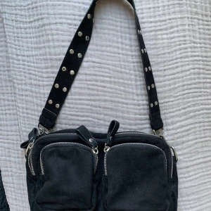 Väska - Säljer denna nya väska, endast använd vid ca 4 tillfällen. Inga skavanker eller slitningar då den är ny. Med följer ett kort band med ”nitar” på och ett långt. Skriv för mer info (kan även tänka mig att byta mot vad som)