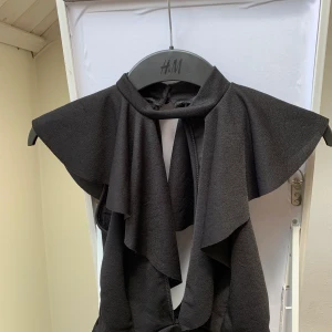 Urringad topp - En urringad topp med öppen rygg som sätts ihop med två knappar baktill. Kragen sitter nära halsen. 