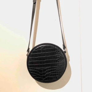  - Svart rund väska i faux ormskinn! Silvrig dragkedja och reglerbart axelband. Ett stort fack som får plats med mycket. Superfint skick, nästintill ny! Frakt tillkommer💞