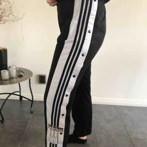  - Snygga Adidasbyxor med knappor längs sidorna på benen. En liten fläck på vänstra benet men verkligen inget man ser om man inte kollar nära. Köparen står för frakt🥰