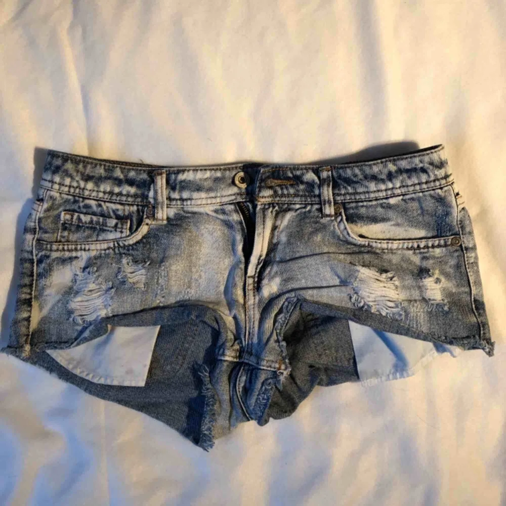 Blåa jeansshorts med slitningar och vita ”fläckar”. Är i använt begagnat skicka men inga fläckar eller liknande. Köparen betalar frakten. Shorts.