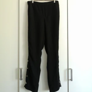  - Snygga svarta byxor med knappar längs sidorna! I priset ingår frakt 😊🌻