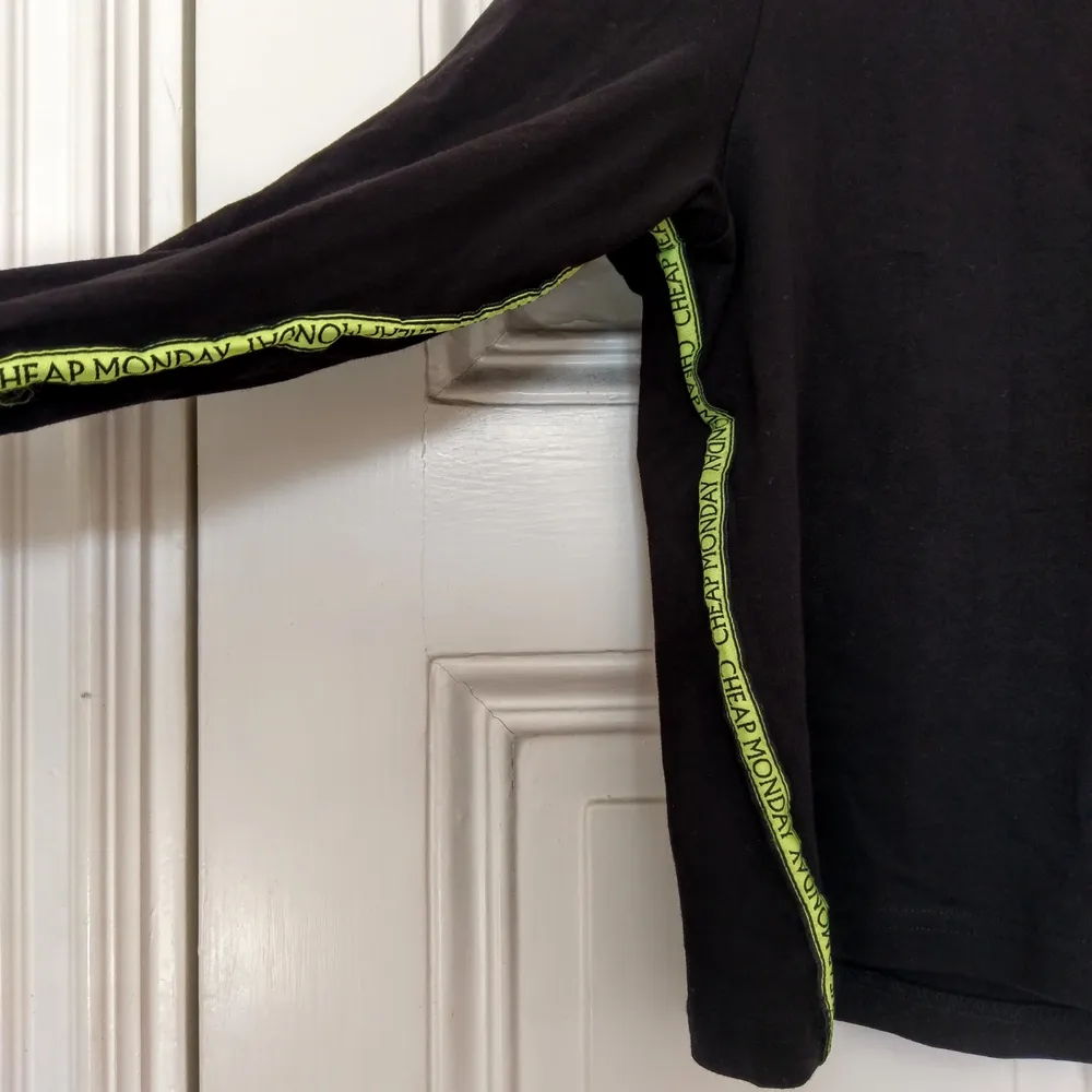 Långärmad, svart tröja med neongröna revärer från Cheap Monday.  Mycket sparsamt använd! 100% ekologisk bomull✨  . Toppar.