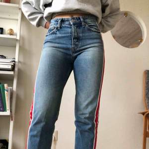 Snygga jeans med röd/blå/vit rand på sidan. Passformen är normal och modellen är straight/momjeans! Frakt tillkommer