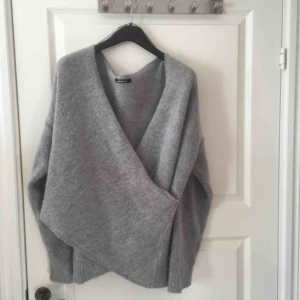  - En grå stickad omlott tröja i st L. Nästan aldrig använd. Köparen betalar frakten