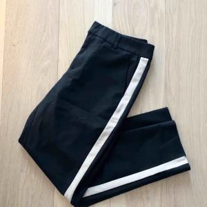  - Säljer ett par snygga svarta ankellånga kostymbyxor med en beige rand på sidan! 