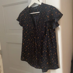 Söt blommig blus storlek 38 M - Fin blus i blommigt mönster storlek 38/M. Faller så fint på kroppen! Mörkblå med orangea blommor! 🌸