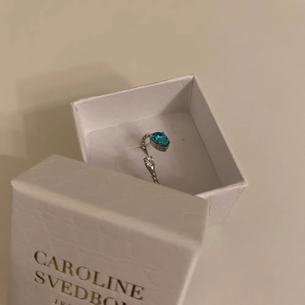 SÅÅÅ fin ring från Caroline Svedbom i silver och färgen light turquoise på stenen. Jätte jättefin och bara använd en gång!!! Ordninarie pris: 350kr. Anledningen till varför jag säljer den är för att jag är en guldtjej och har örhängena i guld så vill därmed köpa ringen i guld i stället. Ringen är anpassbar så man kan ändra om passformen beroende på finger. Säljare står för fraktkostnad!💓 . Övrigt.