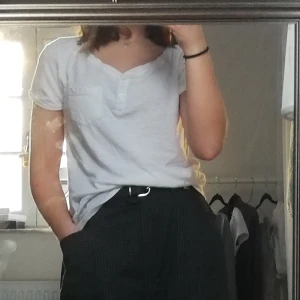 Vit Hollister t-shirt XS - Säljer en vit hollister t-shirt med knappar och en ficka på bröstet. Använd men i hyfsat bra skick ändå, lite nopprig dock. Storlek XS, lite pösig😚