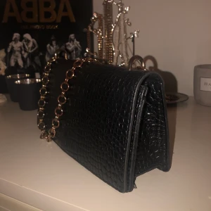 svart axelväska - frakt ingår i pris! suuupersnygg och rymlig axelväska. guldfärgen från kedjan har lossnat på vissa delar, men inget man tänker på. försluts med magnetisk knapp. litet fack finns i väskan :) 